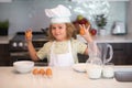 Kid chef cook with eggs at kitchen. Child chef cook prepares food at kitchen. Kids cooking. Teen boy with apron and chef Royalty Free Stock Photo