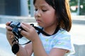 Kid, Child, Asian little girl holding and looking at the digital camera, learn how to take a photo Royalty Free Stock Photo