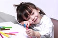 The girl is smiling and pointing her finger  Have a crayon in her hand  While coloring Royalty Free Stock Photo
