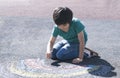 Kid colouring rainbow on pavement, Child drawing rainbow with colourful chalks on footpath during Covid-19 quarantine at home,Home