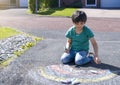 Kid colouring rainbow on pavement, Child drawing rainbow with colourful chalks on footpath on his own during quarantine at home,