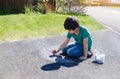 Kid colouring rainbow on pavement, Child drawing rainbow with colourful chalks on footpath on his own during quarantine at home,