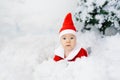 The kid in the costume of little Santa lies in the artificial snow. He`s surprised. Christmas sales Royalty Free Stock Photo