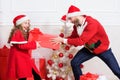 Kid cute girl play with father near christmas tree. Playful daughter and dad celebrate christmas. Winter activity and Royalty Free Stock Photo