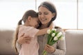 Kid daughter hugging mom holding tulips congratulating with mothers day Royalty Free Stock Photo