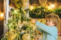 Kid decorating Christmas tree with bauble. Christmas decorations. Portrait of Santa kid with bauble looking at camera Royalty Free Stock Photo