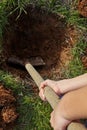 Kid digs with shovel a hole for tree planting. Royalty Free Stock Photo