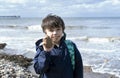 Kid with dirty mount of chocolate ice cream showing stone to the beach on spring or summer, Child boy playing with the rock, Royalty Free Stock Photo