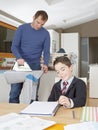 Kid doing homework, dad ironing. Royalty Free Stock Photo