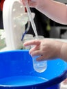 Kid doing scientific experiment at home with liquids holding a test tube and a pasteur pipette. Hands close-up, the concept of