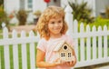 Kid dreaming of new home. Happy boy holding dream house in their hands, real estate and home insurance concept. Royalty Free Stock Photo