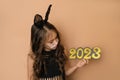 Kid dressed up as black rabbit holds in hands golden numbers of new year 2023