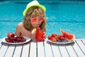 Kid drink cocktail, strawberry smoothie in the pool. The child has a rest in swimming pool. Summer cocktail and fruits Royalty Free Stock Photo