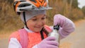 Kid drink water from an aluminum flask. One caucasian children rides bike road in autumn park. Little girl riding black Royalty Free Stock Photo