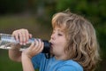 Kid drinking water outdoor. Close up portrait of boy drink water from bottle in the garden. Royalty Free Stock Photo