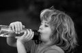 Kid drinking water outdoor. Close up portrait of boy drink water from bottle in the garden. Royalty Free Stock Photo