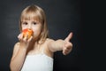 Kid eating fresh red apple happy and doing ok sign, thumb up with fingers, excellent sign