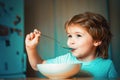 Kid eating. Little boy having breakfast in the kitchen. Parenthood. Happy child. Young kid sitting on the table eating