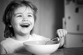 Kid eating. Little boy having breakfast in the kitchen. Smiling happy adorable baby eating fruit mash in the kitchen Royalty Free Stock Photo