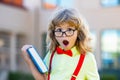 Kid from elementary school. Happy boy in glasses is going to school for the first time. Child with school bag and book Royalty Free Stock Photo