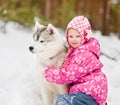 Kid embracing hasky dog in winter park