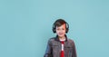 Kid enjoying music on his headphones, listening to music. Handsome young stylish kid in headphones standing against blue backgroun Royalty Free Stock Photo