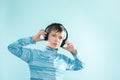 Kid enjoying music on his headphones, listening to music. Handsome young stylish kid in headphones standing against blue backgroun Royalty Free Stock Photo