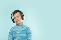 Kid enjoying music on his headphones, listening to music. Handsome young stylish kid in headphones standing against blue backgroun Royalty Free Stock Photo
