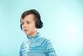 Kid enjoying music on his headphones, listening to music. Handsome young stylish kid in headphones standing against blue backgroun Royalty Free Stock Photo