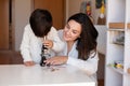 Kid exploring science with a microscope and mother or teacher help. Homeshooling. Learning Community. Montessori School