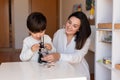 Kid exploring science with a microscope and mother or teacher help. Homeshooling. Learning Community. Montessori School