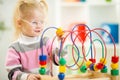 Kid in eyeglases playing colorful toy in home