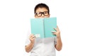 Kid with eyeglasses hiding face behide book and looking at camera Royalty Free Stock Photo