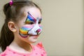 Kid with face painting of kitty, cute little girl with painted mask on face of rainbow cat Royalty Free Stock Photo