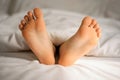 Kid feet sticking out from under the blanket in the morning light. Close up