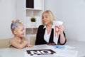 Kid with female speech therapist in the white cabinet.