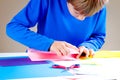 Kid folding colored paper and making origami.