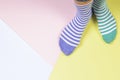 Kid foots in mismatched stripped socks on colorful background. Odd Socks day, Anti-Bullying Week, Down syndrome