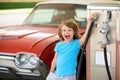 Kid fueling retro car at gas station. Refuel fill up with petrol gasoline. Petrol pump filling fuel nozzle in fuel tank Royalty Free Stock Photo