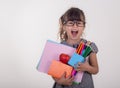 Kid gets ready for school. Schoolgirl holding many school supplies: pens, notebooks, scissors and apple. Back to school concept. Royalty Free Stock Photo