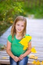 Kid girl in autumn wood deck with yellow leaves outdoor Royalty Free Stock Photo