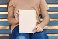 Kid girl in beige t-shirt sitting on a beench and holding notebook in hands