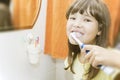 Girl brushing her teeth with toothpaste. Smiles and looks into the lens