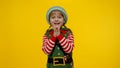 Kid girl child in Christmas elf Santa helper costume laughing on yellow background. New Year holiday