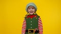 Kid girl child in Christmas elf Santa helper costume laughing on yellow background. New Year holiday