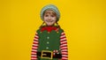 Kid girl child in Christmas elf Santa helper costume smiling on yellow background. New Year holiday