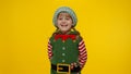 Kid girl child in Christmas elf Santa helper costume smiling on yellow background. New Year holiday