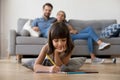 Kid girl drawing on floor with family in living room Royalty Free Stock Photo