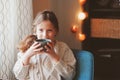 Kid girl drinking hot cocoa at home in winter weekend, sitting on cozy chair