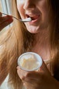 Kid girl eating tasty yogurt at home.